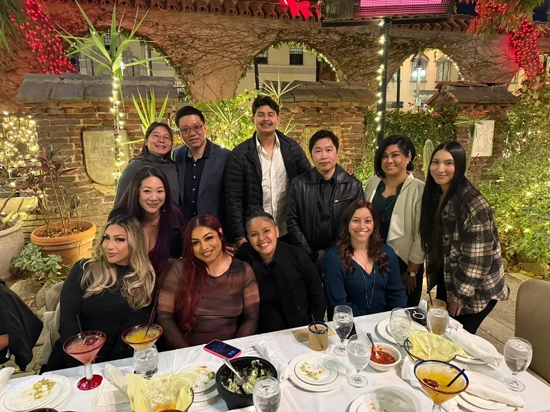 Group photo of office staff at Christmas Dinner Party standing behind table
